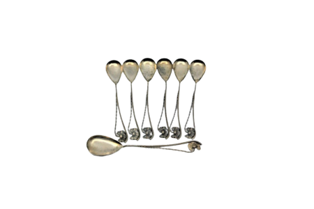 Conjunto de seis colheres de café e pá de açúcar em prata com conchas douradas e cabos vazados com motivos florais.